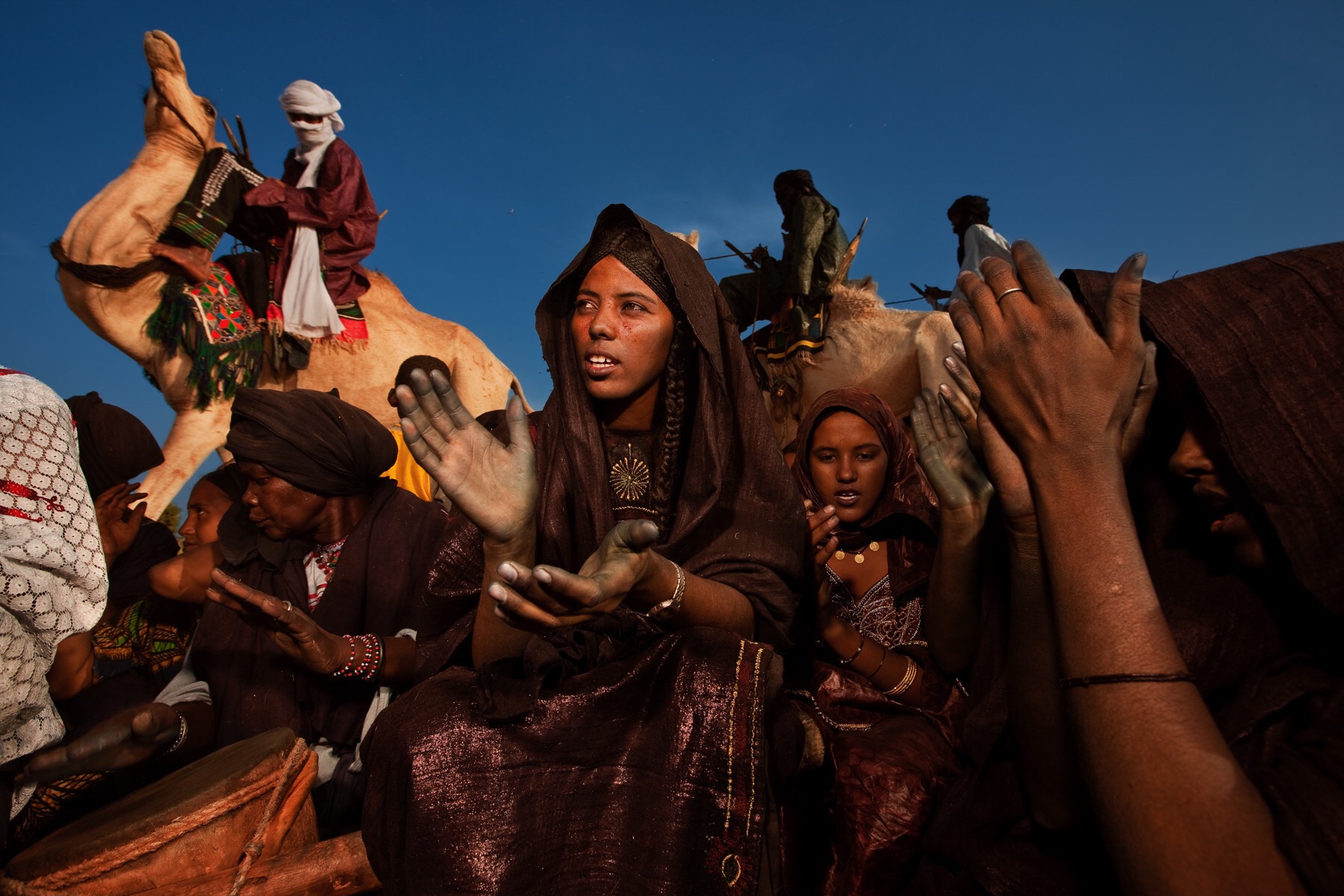 INGAL, NIGER, OCTOBER 2009: Scenes at a Baptism in a Tuareg Nomad camp, Ingal Region, Niger, 11 October 2009. Tuareg Baptism is very simple, three names are discussed by elders and then straws are drawn to choose the final name. The women perform a ritual of walking around the tent in a line with the leading woman brandishing two knives to symbolically cut away misfortune from the future of the child. The women then dance and sing and play the drums while men prepare goat mead and drink tea and discuss things while people visit from the surrounding nomad camps. Tuareg Nomads have two traditional priorities, their animals and access to water. This group has moved to this region at this time to enjoy the remaining good grassland of the rainy season and will soon move again to be close to a good water source. The nomads survive on a diet of millet and camel milk which is occasionally supplemented by goat meat. (Photo by Brent Stirton/National Geographic.)